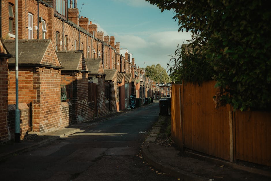 A broad view of a residential area on a hillside showing multiple layers of houses with pitched roofs, some with chimneys and dormer windows, in a mix of brick, painted wood, and tile materials. The h